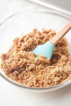 a wooden spoon in a glass bowl filled with crumbs