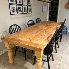 a wooden table surrounded by black chairs in a room with pictures hanging on the wall