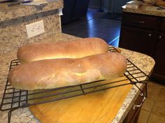 two loaves of bread sitting on top of a cooling rack next to a counter