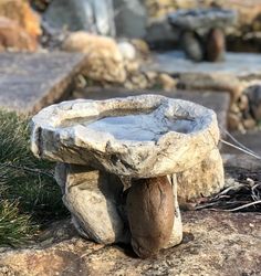 a stone table sitting on top of a rock covered ground next to grass and rocks