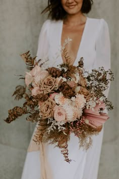 a woman in a white dress holding a large bouquet with flowers on it's side