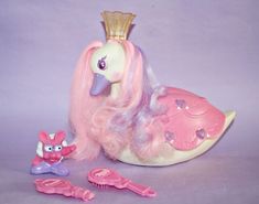 a pink pony with a crown on its head next to other toys and hairbrushes