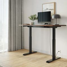 a computer desk with a monitor and keyboard on it, in front of a window