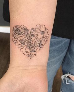 a heart shaped tattoo with flowers on the wrist