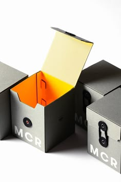 two open boxes sitting next to each other on top of a white surface, one with an orange folder in it