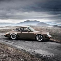 a brown car parked on top of a dirt road