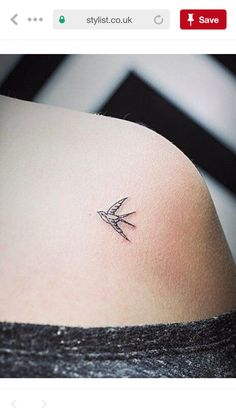 the back of a woman's shoulder with a small tattoo on her left side