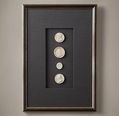 three white buttons in a black frame hanging on the wall