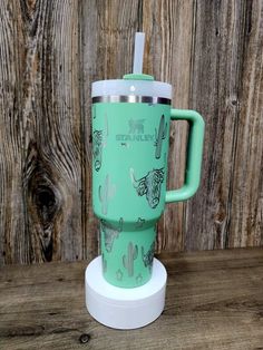 a green travel mug sitting on top of a wooden table