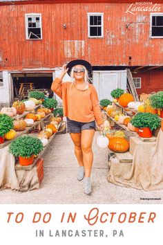 a woman in an orange sweater and black hat is walking through a farmers market filled with pumpkins