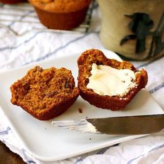 two muffins on a plate with butter and a knife