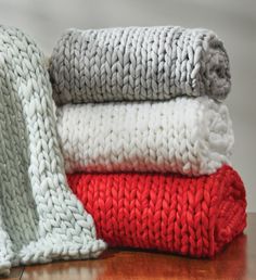 three knitted blankets stacked on top of each other, one red and one white