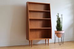 a wooden book shelf next to a potted plant