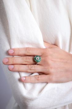 a woman's hand with a green ring on her left wrist and white shirt