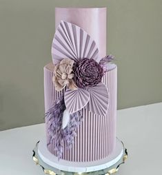 a three tiered cake decorated with flowers and feathers