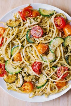 a plate of pasta with zucchini and tomatoes