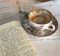 a cup of coffee sitting on top of a saucer next to an open book