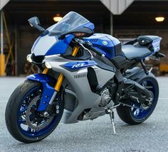 a blue and silver motorcycle parked in front of a garage