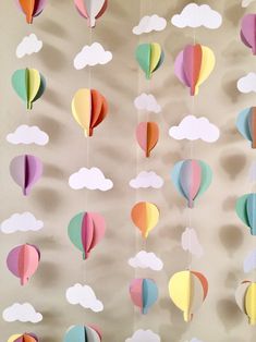 paper hot air balloons are hanging from the ceiling with clouds in the sky above them