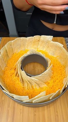 a person holding a cell phone near a bowl filled with cheese and tortilla wrappers