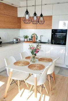 a kitchen table with four chairs and a vase filled with flowers on top of it