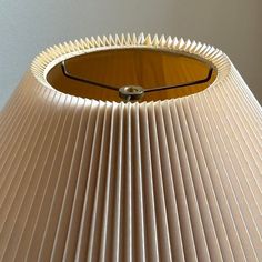 a lamp shade that is made out of pleated paper and has a round hole in the middle