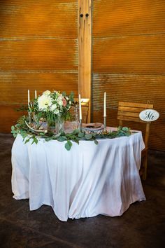 the table is set with candles, flowers and greenery for an elegant wedding reception