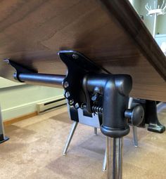 a close up of a table with metal legs and a wooden top on the floor