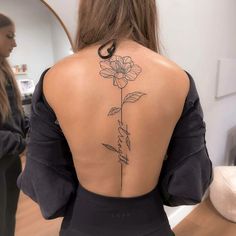 the back of a woman's body with a flower tattoo on her left shoulder