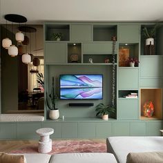 a flat screen tv sitting on top of a wooden shelf in a living room filled with furniture