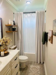 a bathroom with a white toilet sitting next to a bath tub under a shower curtain