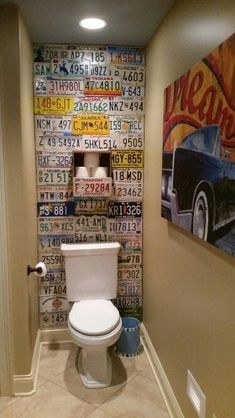 a toilet in a bathroom next to a wall with license plates on it