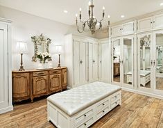 a large white bedroom with mirrored closets and chandelier in the middle of it