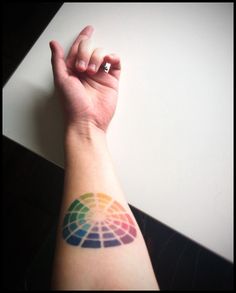 a person's arm with a rainbow colored tattoo on the left side of their arm