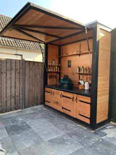 an outdoor kitchen is built into the side of a house with wooden cabinets and shelves