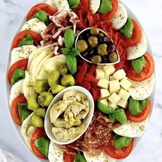 a platter filled with olives, tomatoes, cheese and other foodstuffs