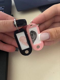 a woman holding a pink and white key chain with a fingerprint on it, in front of a computer keyboard