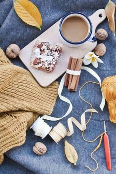 a cup of coffee sitting on top of a table next to some cinnamons and nuts