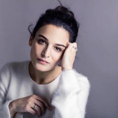 a woman in a white sweater holding her hand to her ear