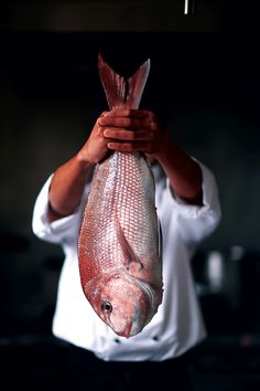 a man holding up a fish in his hands