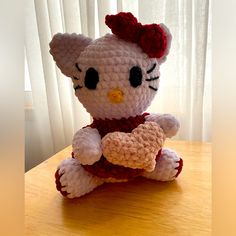 a crocheted hello kitty sitting on top of a table next to a window