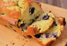 a loaf of blueberry bread sitting on top of a wooden cutting board