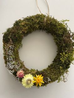 a moss wreath with flowers hanging from it