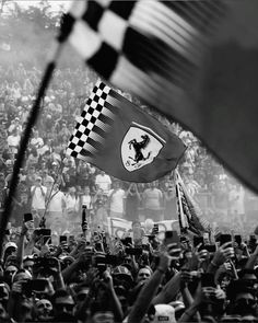 black and white photograph of people waving flags in front of a large crowd at a sporting event