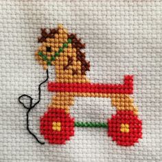 a cross stitch pattern with a lion on it's side and a thread spool in the middle