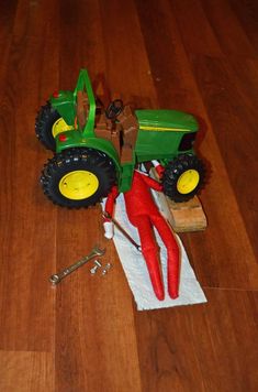 a green toy tractor sitting on top of a wooden floor