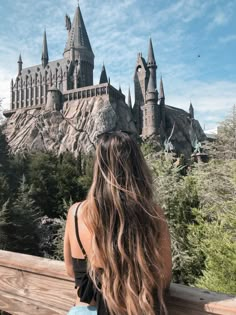 a woman sitting on a bench looking at hogwarts castle