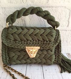 a green handbag sitting on top of a white table next to a chain strap