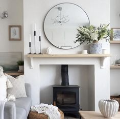 a living room filled with furniture and a fire place in front of a round mirror