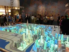 a group of people standing around a model of a city